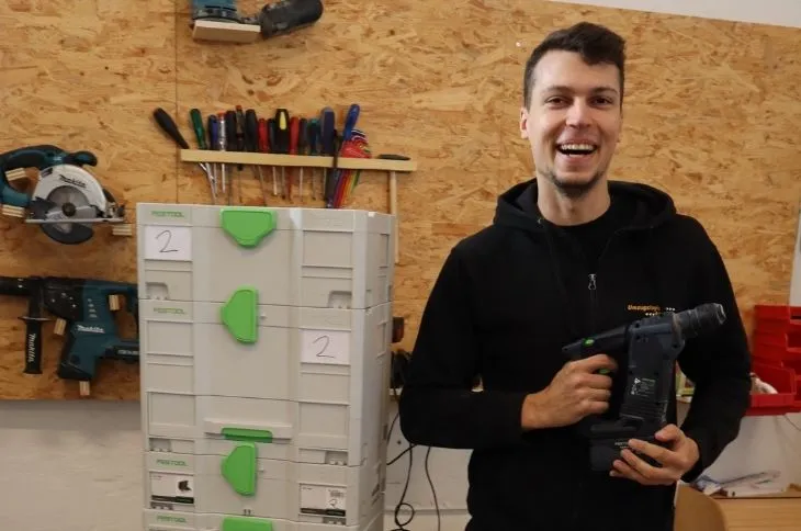 gluecklicher umzugshelfer haelt bohrmaschine in der hand